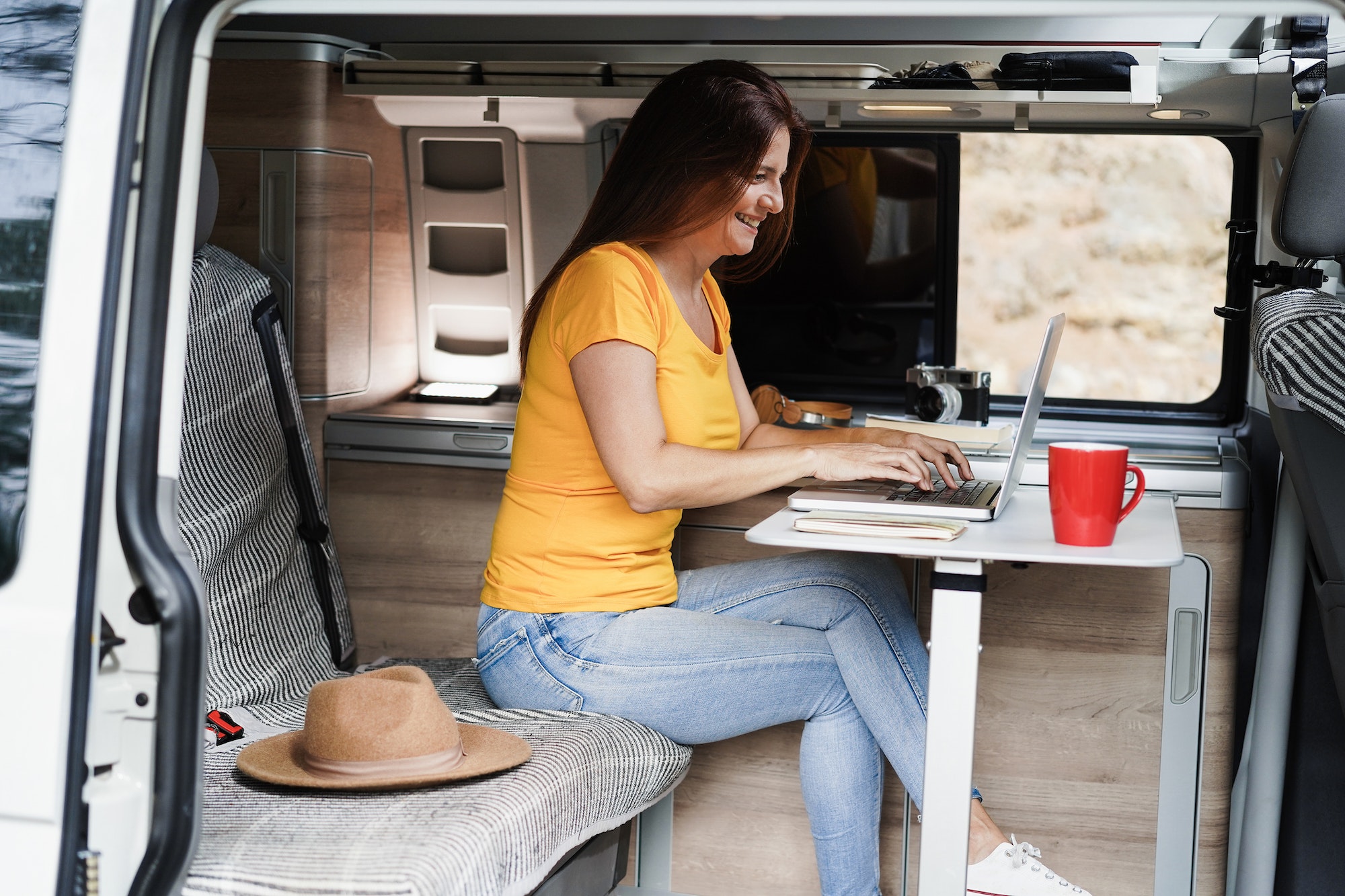 Femme travaillant sur un PC dans un fourgon aménagé