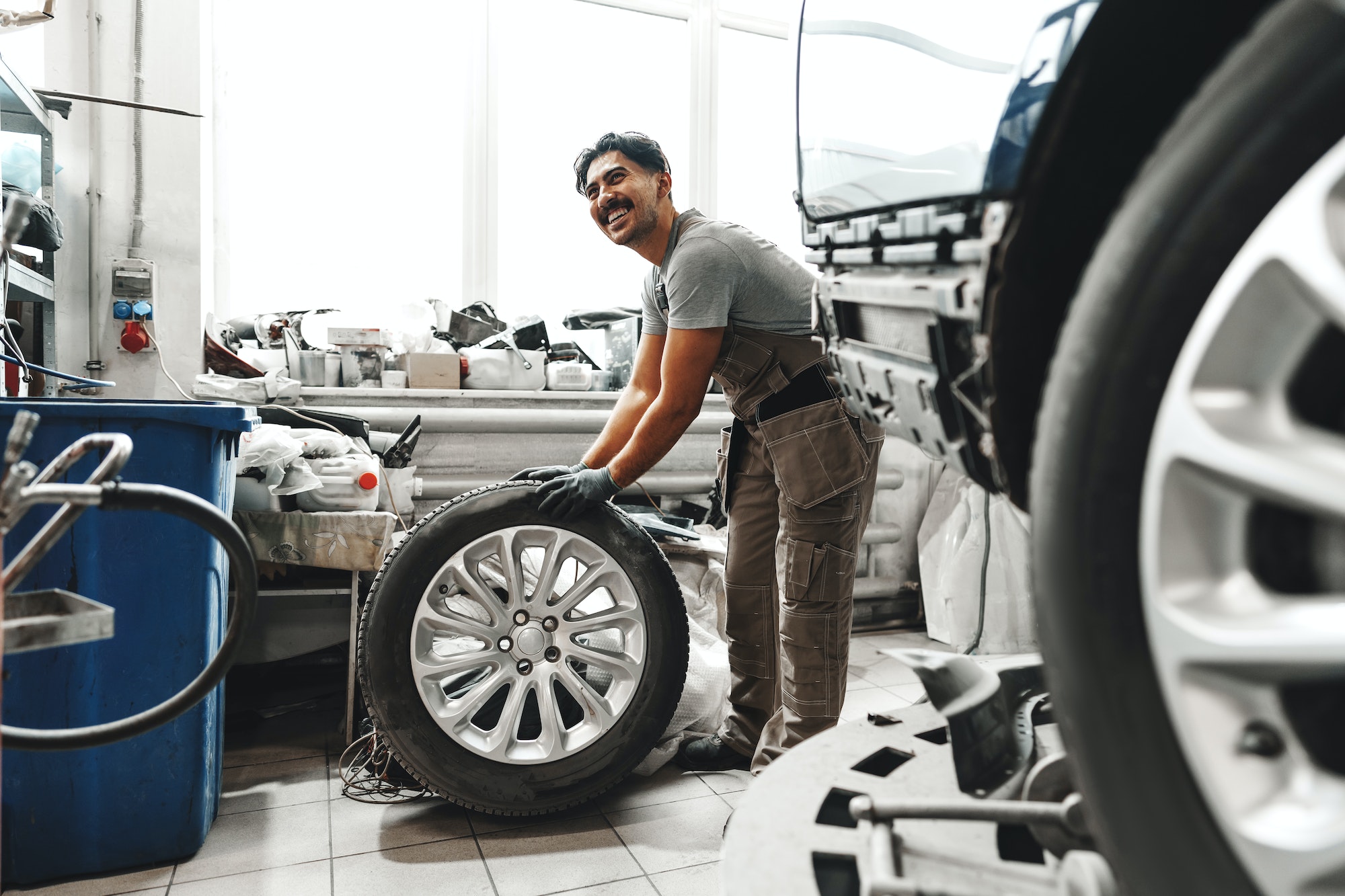 Mécanicien souriant monte des pneus neufs