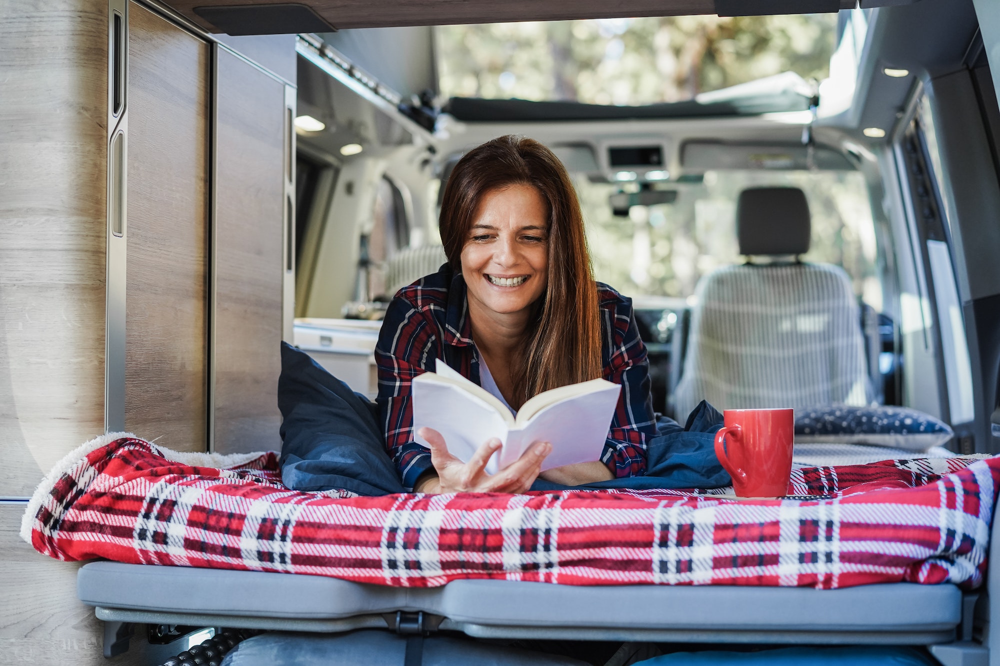 Femme avec son livre et son café dans un camping-car