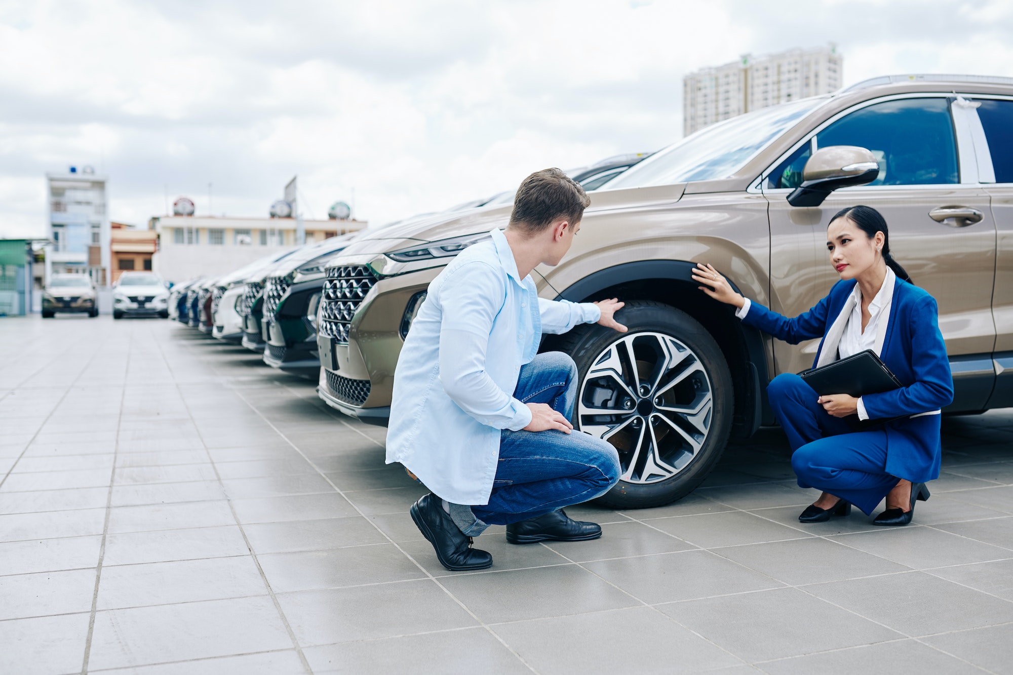 Vendeuse et acheteur vérifiant les pneus d'une voiture